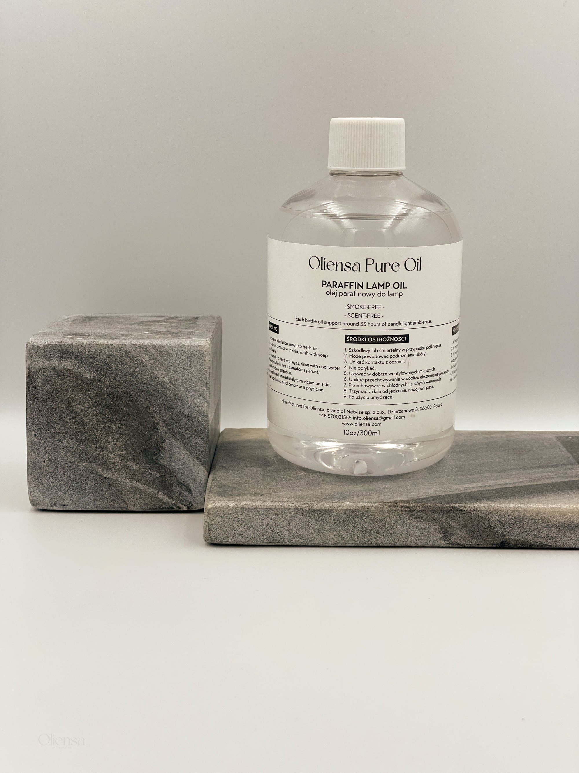 Zdjęcie produktowe, packshot krystalicznego oleju mineralnego Oliensa Pure Oil. Widok przodu butelki na marmurowym kamieniu