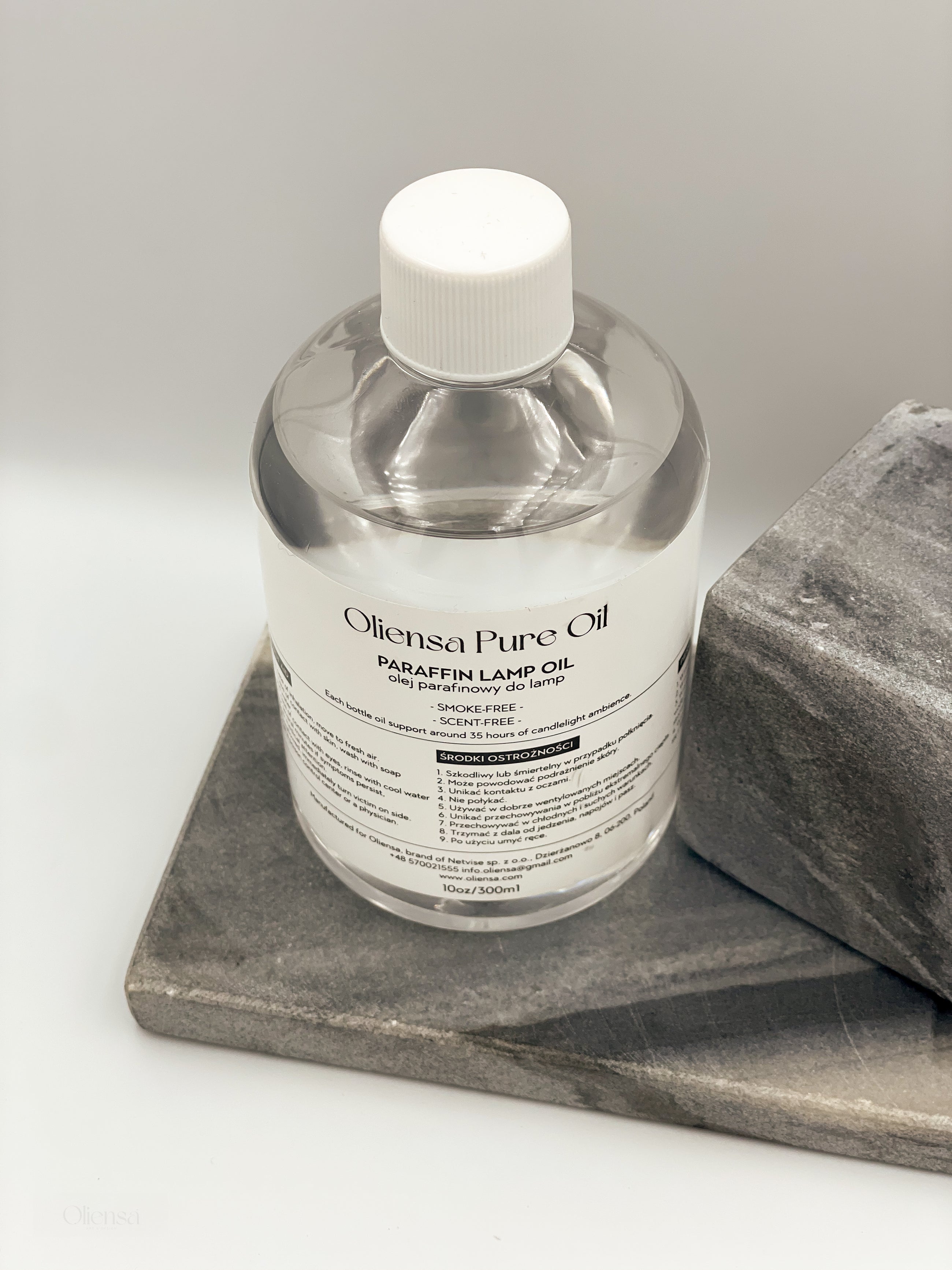 Zdjęcie produktowe, packshot krystalicznego oleju mineralnego Oliensa Pure Oil. Widok całej butelki na marmurowym kamieniu