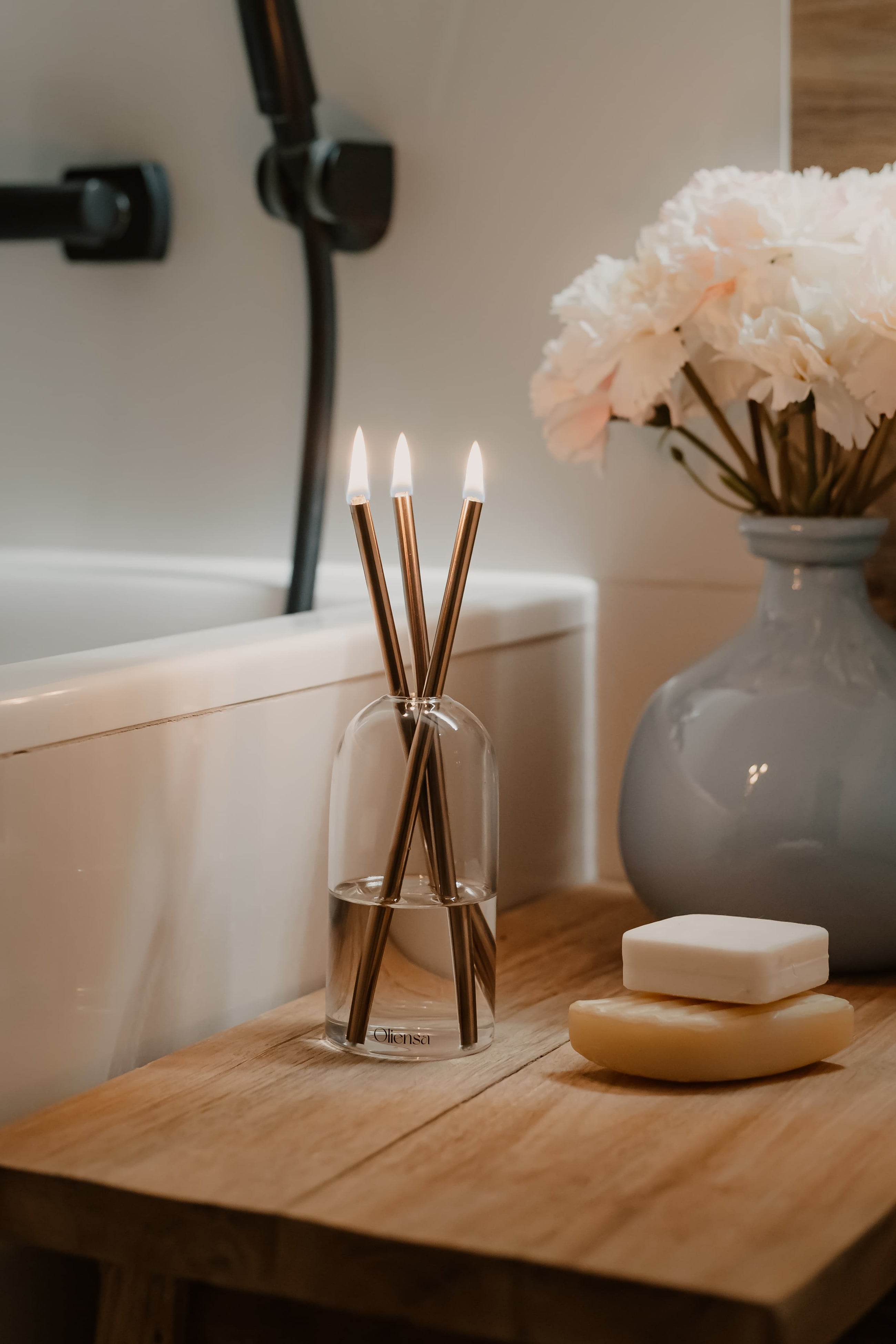 Świeca Oliensa Crystal Copper w łazience – ustawiona przy wannie i naturalnym mydle, tworzy atmosferę spokoju, intymności i luksusowego rytuału.